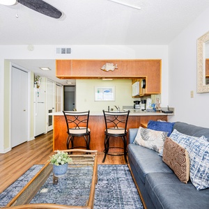 This inviting living area features a comfortable sofa, stylish decor, and a view of the kitchen with a breakfast bar