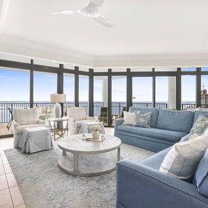 This living area features soft blue furnishings, a cozy coffee table, and stunning beach views through expansive windows