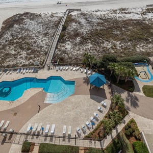 Relax by the inviting pool surrounded by lounge chairs and lush landscaping, just steps from the beach access