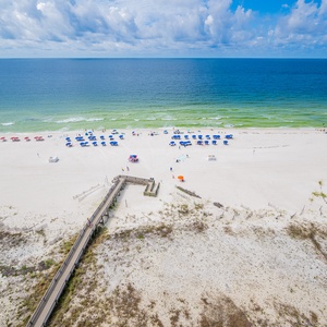 Enjoy the view of the beach dotted with colorful umbrellas and the inviting waves lapping at the shore