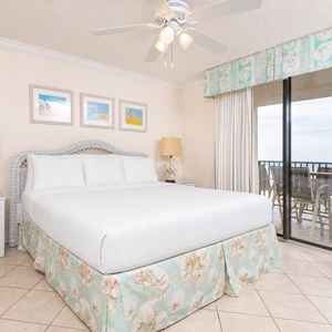 Relax in the spacious master bedroom featuring a king bed, coastal decor, and beachfront balcony access