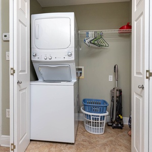 Laundry area featuring a stacked washer and dryer, storage shelves, and laundry baskets for convenient in-unit cleaning