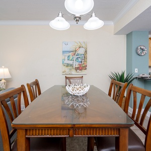 Dining area with a wooden table, cozy seating, and beach-themed decor, perfect for family meals and gatherings