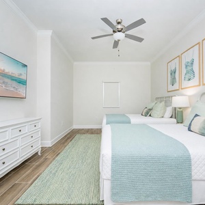 Relax in this guest bedroom featuring two queen beds, decorative pillows, and beach artwork