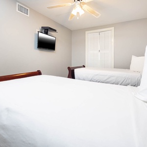 Rest in this comfortable guest bedroom featuring two twin beds, a flat-screen TV, and a ceiling fan