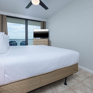 This bedroom features a plush bed, a TV for entertainment, and a balcony view with seating for relaxation