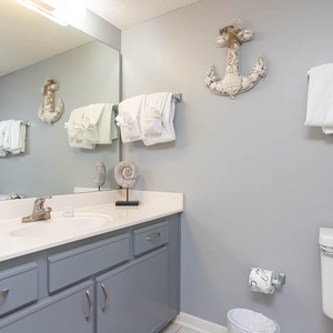 The guest bathroom features a light gray color scheme, a spacious vanity with a large mirror, and fresh plush towels