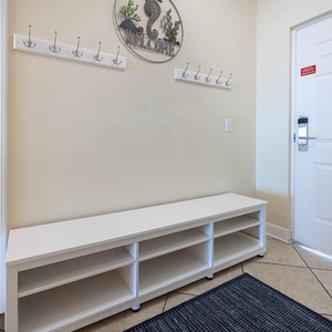 This welcoming entryway features a white bench, coat hooks, and a decorative wall piece, creating a warm first impression