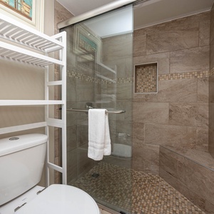 The master bath features a sleek walk-in shower with elegant tile work and ample shelving for your essentials