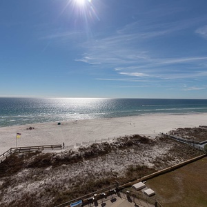 Stunning beachfront view showcases white sand and gentle waves under a bright sky, perfect for relaxation and enjoyment