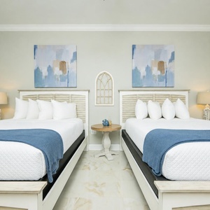 Serene guest room featuring two queen beds, soft pillows, and elegant design