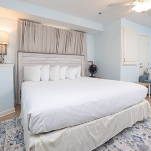 Master suite featuring a king bed, a cozy blue sofa with queen sleeper, and soft blue walls, creating a tranquil atmosphere