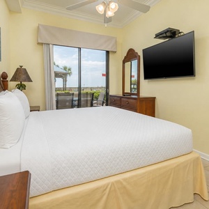 Enjoy restful nights in the master bedroom, featuring a king bed, TV, and views of the inviting beachfront patio