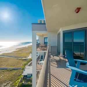 Balcony with blue chairs offers a tranquil view of the beach and sparkling gulf waters under a clear sunny sky