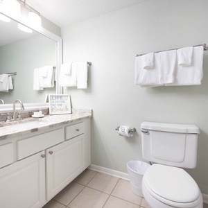 The guest bath features a marbled countertop, a large mirror, and fresh towels, creating a clean and refreshing atmosphere