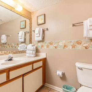Guest bath featuring a spacious countertop, decorative seashell accents, and neatly arranged towels for a refreshing stay