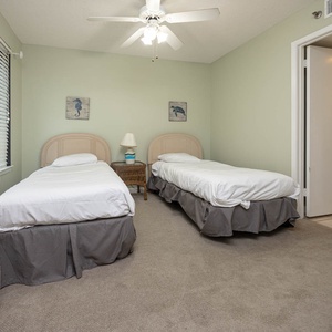 This guest room features two twin beds, soft beige walls, and a cozy atmosphere enhanced by natural light from the window