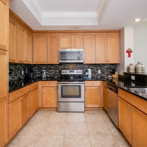 Prepare meals in the warm-toned kitchen, featuring sleek appliances, coffee corner, and stylish backsplash