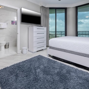 Inviting guest bedroom featuring a queen bed, a large TV, and expansive windows for scenic views