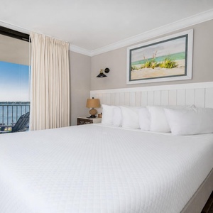 Master bedroom featuring a plush king bed and stunning views of the water through large sliding glass doors