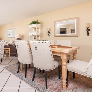 The dining area features a rustic wooden table surrounded by elegant upholstered chairs, creating a welcoming atmosphere