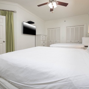 Relax in this peaceful guest bedroom featuring two comfortable queen beds, a flat-screen TV, and ample storage