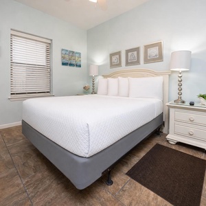 Brightly decorated guest bedroom featuring a queen bed, stylish nightstand, and coastal artwork, creating a serene retreat