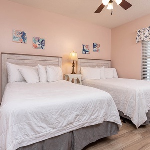 Sleep peacefully in this inviting guest room with two double beds, beach decor, and natural light from the window