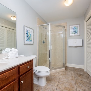 The extra bath features a sleek glass walk-in shower, elegant cabinetry, and laundry area with a washer and dryer