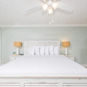 This aesthetic master bedroom features a large king bed, stylish lamps, and a charming dresser with beach balcony access