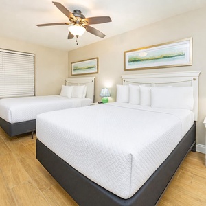 Bask in comfort on plush queen beds, sharing quiet moments and restful nights in this inviting guest bedroom
