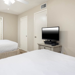 Relaxing guest bedroom featuring two queen beds, a TV, and easy access to the bathroom