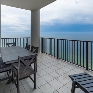 This outdoor balcony area features a large table and chairs, perfect for enjoying meals with a stunning beachfront view