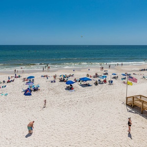 This vibrant beachfront view showcases a lively scene with colorful umbrellas and beachgoers enjoying the sun and sand
