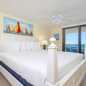 Master bedroom with a king bed, ceiling fan, and balcony access showcasing a serene beachfront view