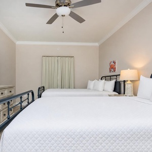 Inviting guest bedroom featuring two queen beds, a large TV, and soft linens for a cozy stay