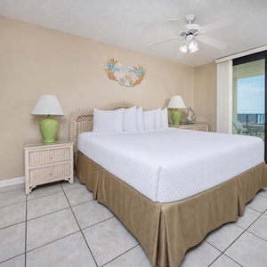 Master suite bedroom features a king bed, tropical accents, and sliding glass doors leading to the extended beach balcony