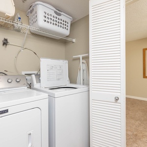 Laundry area featuring a Maytag washer and dryer with a nearby basket and a vibrant artwork enhancing the charm