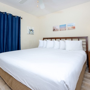 Cozy guest bedroom featuring a king bed, navy curtains, and beach-themed decor for a relaxing getaway experience