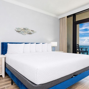 Relax in this master bedroom featuring a king bed, stylish decor, and beachfront balcony access