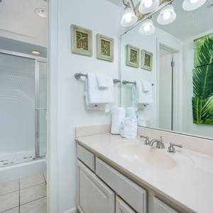 This master bathroom features a spacious vanity, a glass-enclosed walk-in shower, and tropical decor for a refreshing vibe