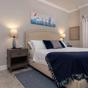 Retreat to the king master suite with fluffy pillows, coastal decor, and soft lighting