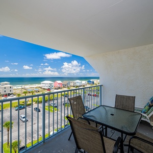 Enjoy a relaxing meal on the balcony with a stunning beach view, featuring a glass table and comfortable seating