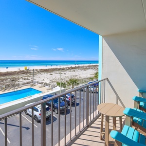 Enjoy breathtaking beach views from this inviting balcony, complete with comfortable seating and a refreshing pool below
