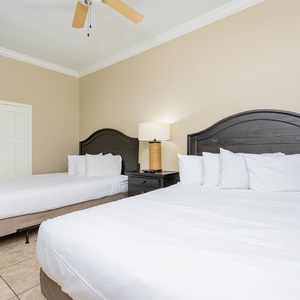 Rest in this inviting guest bedroom featuring two queen beds, a stylish lamp, and warm tones
