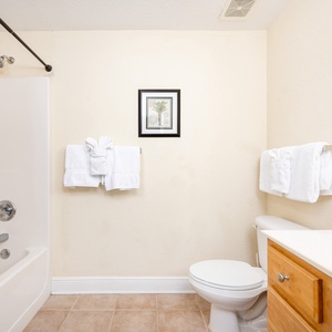 Master bathroom featuring a tub/shower combo, fresh towels, and warm wood accents for a relaxing retreat