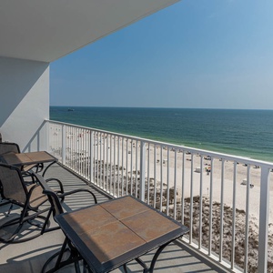 This balcony offers a stunning beach front view, complete with seating for relaxation and enjoyment of the scenery