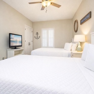 Relax in this cozy guest bedroom, where two queen beds invite you to unwind and catch up on your favorite shows