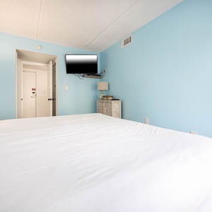 This inviting bedroom features a plush bed, soft blue walls, and a TV, creating a relaxing retreat for guests