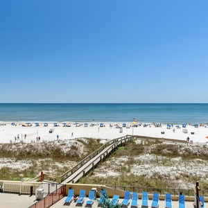 Expansive beachfront view showcasing white sand, colorful umbrellas, and sun loungers along the tranquil shoreline